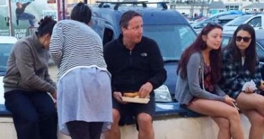 ديفيد كاميرون رئيس وزراء بريطانيا السابق يأكل على الرصيف